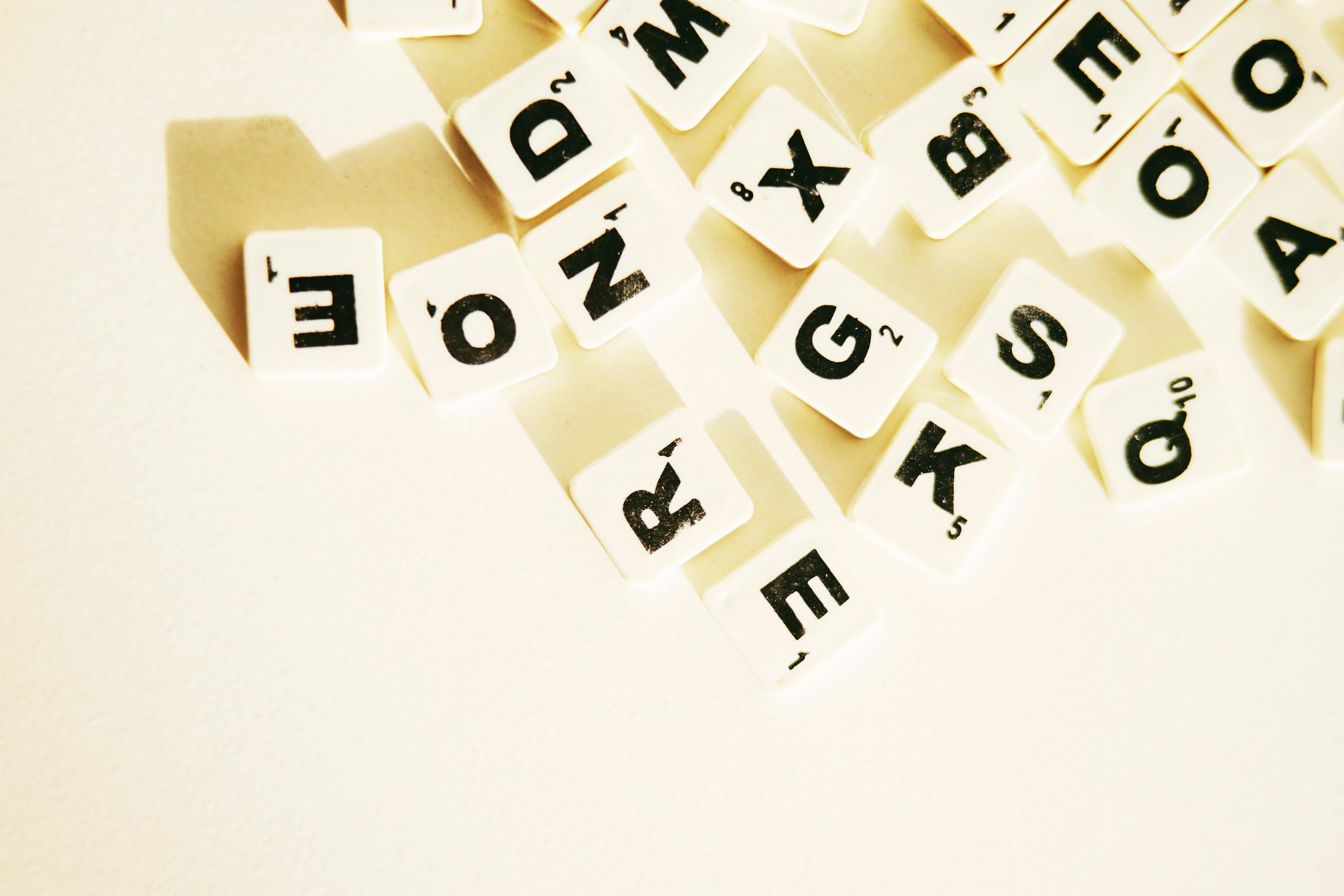Scrabble tiles scattered on a white surface, creating space for text or design.
