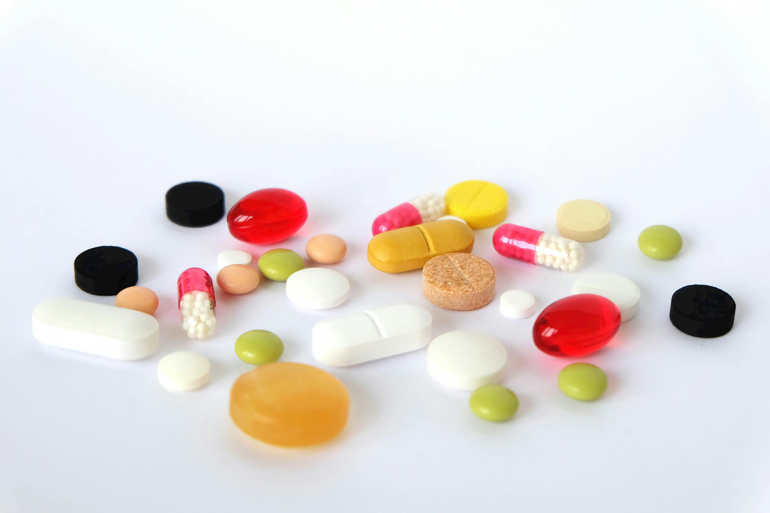 Various colorful pills and tablets scattered on a white surface, representing medication.
